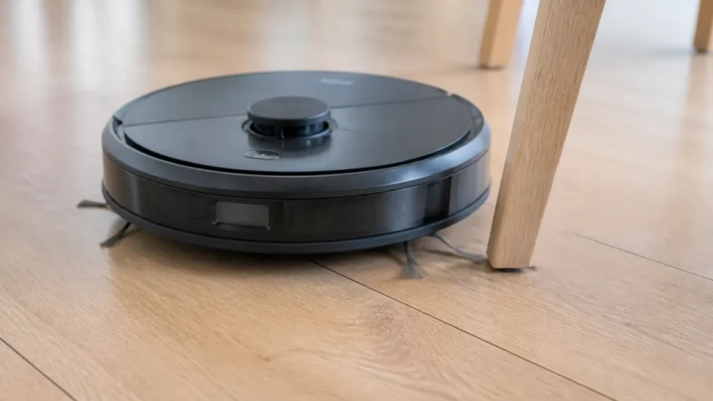 Robot laveur contournant un pied de chaise sur un parquet