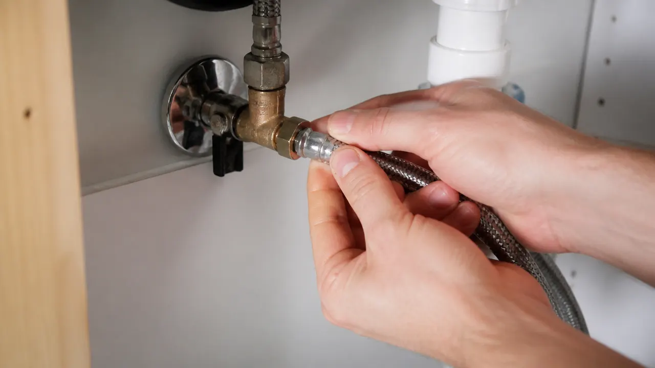 Branchement d'une station raccordée à l'eau sous l'évier Raccordement d'un tuyau d'eau sous un meuble d'évier pour une station autonome